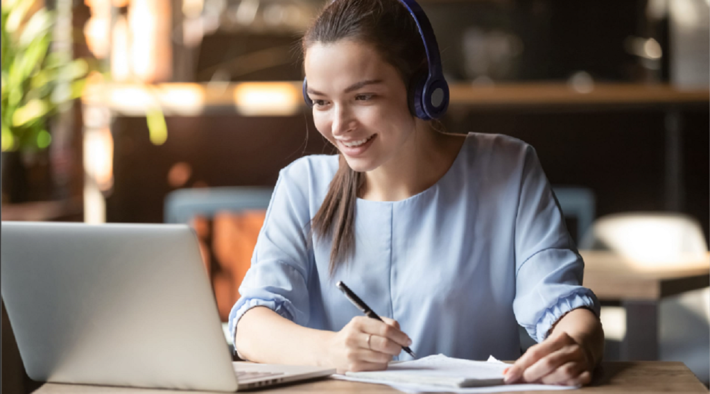 Woman at computer taking notes.