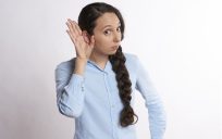 Woman holding her hand up to her ear